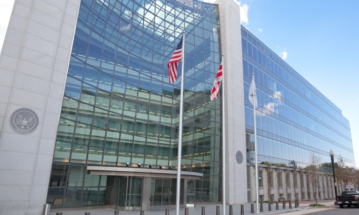 A red stop sign superimposed over a stock market ticker and cryptocurrency symbols.