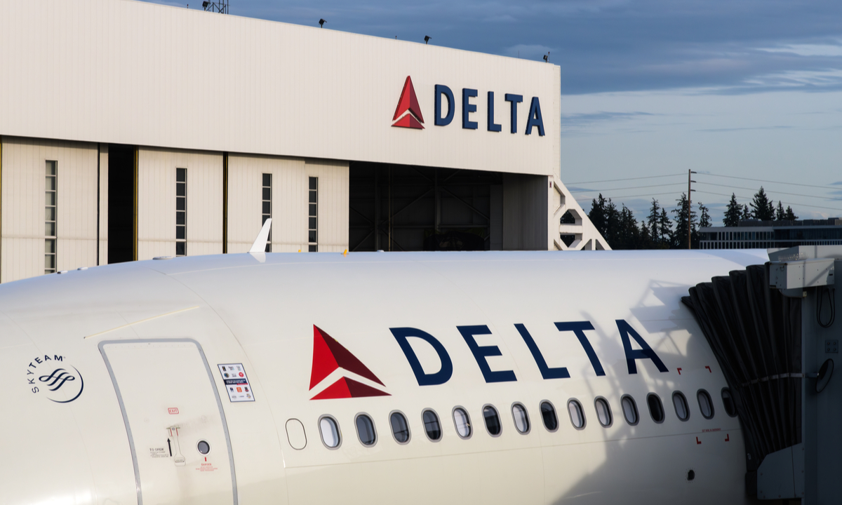 Aereo Delta Air Lines sulla pista con overlay grafico dei prezzi carburante in rialzo