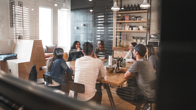 A group of diverse financial professionals collaborating around a table with a tablet displaying charts and data, suggesting technology integration.