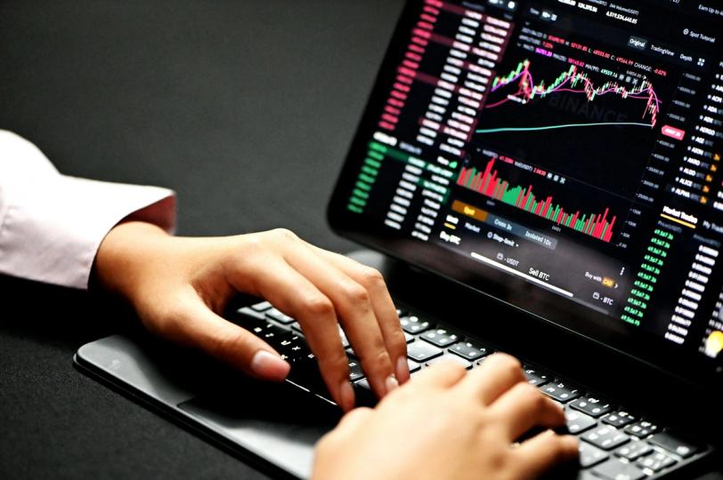 A person using a smartphone to interact with a cryptocurrency exchange interface, with a backdrop symbolizing emerging markets.