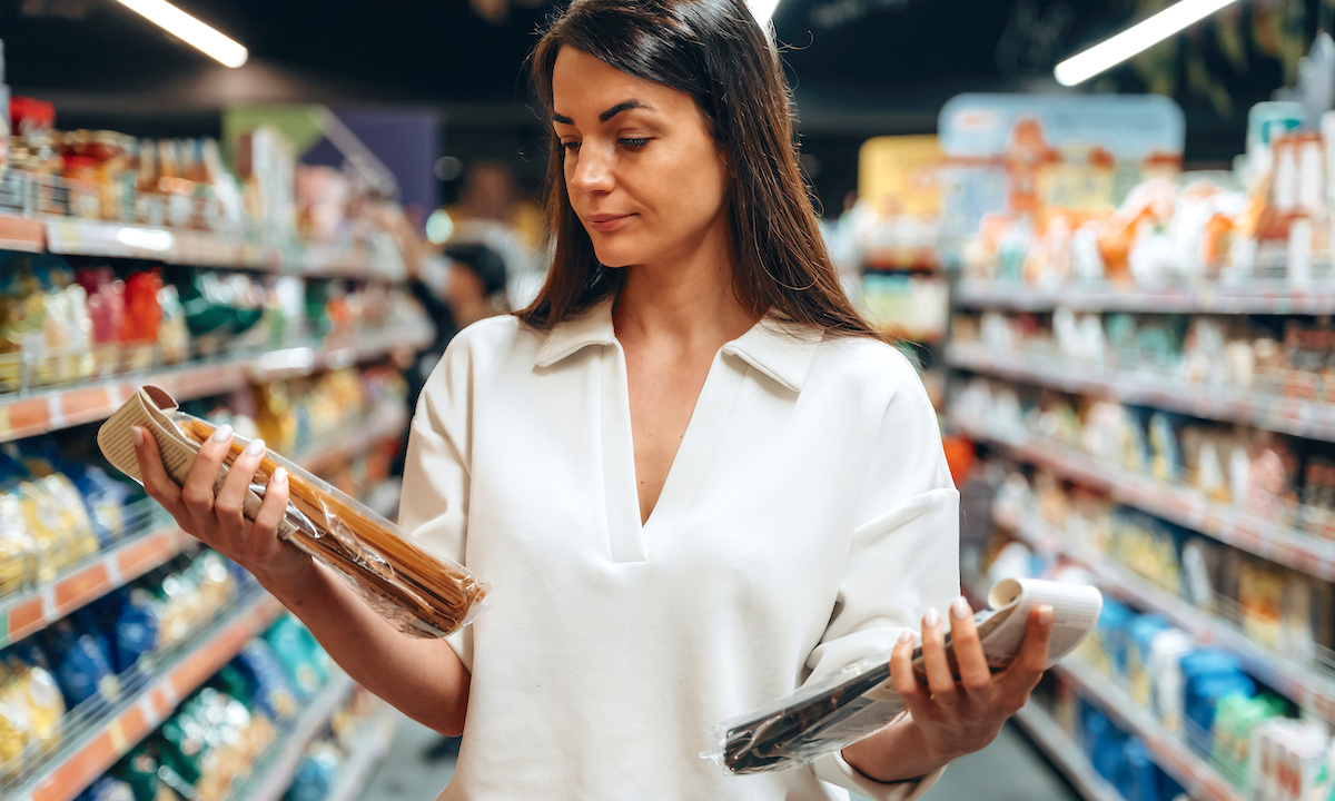 A shopper looking thoughtfully at their phone during a sale, surrounded by digital sale notifications.